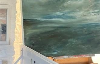 A landscape painting on an easel in an artist's studio