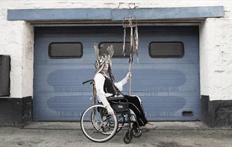 libby bove sitting in a wheelchair in front of a garage doot