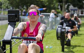 Man rowing on a rowing machine with others behind him.
