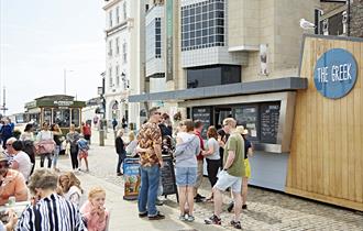 Customer queuing outside The Greek also customers sat at outdoor seating area.