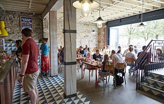 The inside of Boston Tea Party showing customers  at the counter ordering food and drinks and other customers seated at tables.