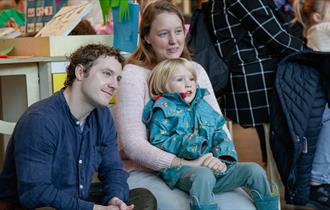 little boy sitting with his parents at the explore more area
