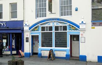 Exterior of The Dolphin with blue painted exterior, stain glass windows and painted dolphins.