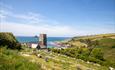 A small church on a grassy hill with sea in the background