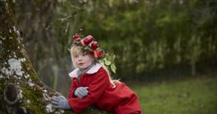 Child wearing a headdress decorated with apples at Avalon Orchard, Glastonbury Tor, Somerset