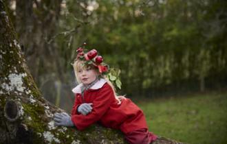 Child wearing a headdress decorated with apples at Avalon Orchard, Glastonbury Tor, Somerset