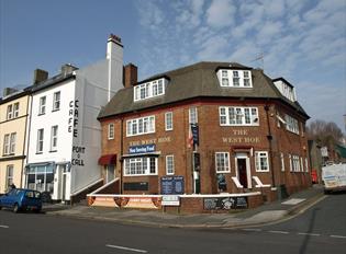 The red brick exterior of the West Hoe, situated on a street corner with the Port o Call Café next door.
