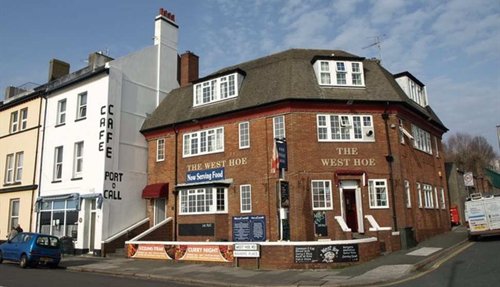 The red brick exterior of the West Hoe, situated on a street corner with the Port o Call Café next door.