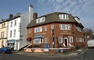 The red brick exterior of the West Hoe, situated on a street corner with the Port o Call Café next door.