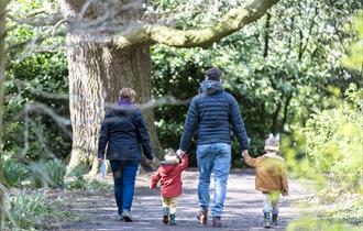 A family of four enjoy walking through Saltram garden completing their Easter trail with bunny ears on their heads.