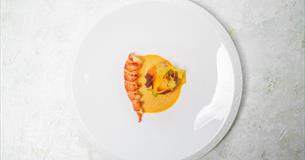 A white plate with a brightly coloured shellfish dish arranged on it.