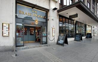 The entrance to the Brass Monkey with chalkboards on the pavement outside.
