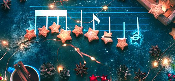 Musical notes have star shaped biscuits placed on top, this is surrounded by Christmas ornaments and foliage.