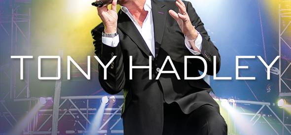 Tony Hadley in a suit singing into a microphone on stage 