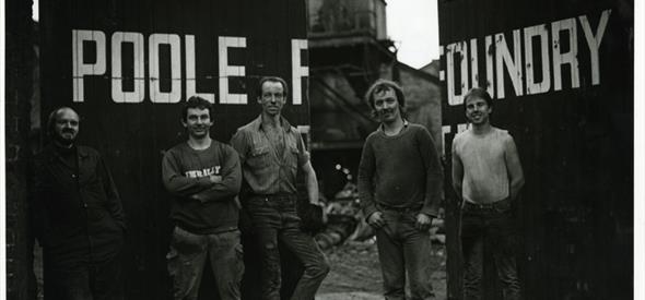 A black and white image with 5 men stood in front of Poole Foundry gates