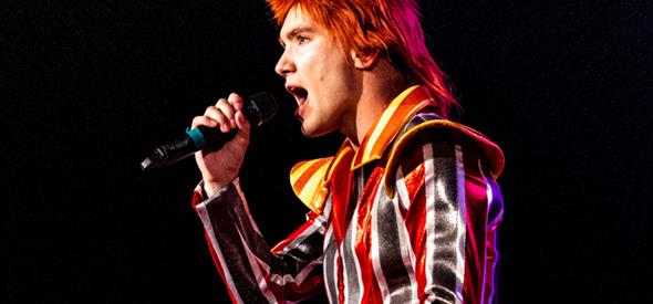 Image of man in a stripe costume, singing in a microphone