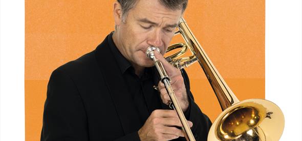 A BSO musician is playing the trumpet in front of an orange graphic.