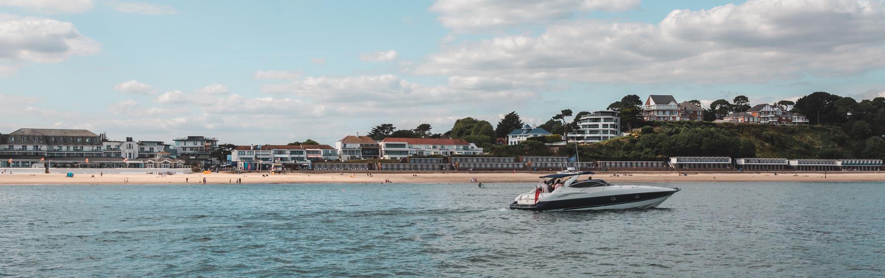 Speedboat pictured travelling along the coast, Sandbanks beach in the  background.