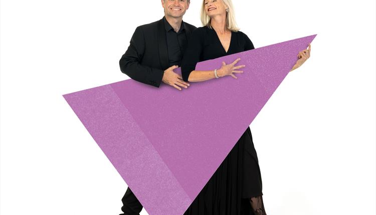 Two musicians are stood holding a purple triangle graphic