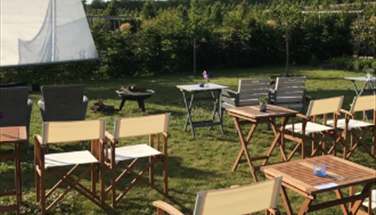 chairs and tables outside in a pretty field in front of a cinema screen