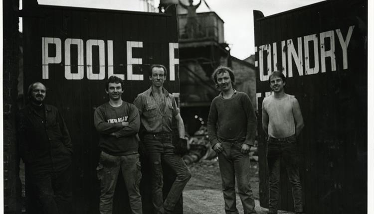 A black and white image with 5 men stood in front of Poole Foundry gates