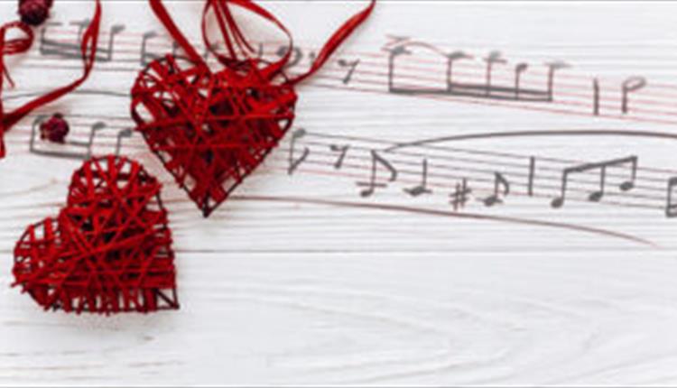 Musical notes painted onto the wooden background and two red wicker hearts are sat on top.