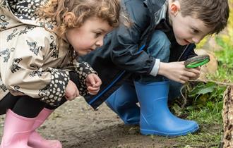 Children exploring nature with a magnifying glass.