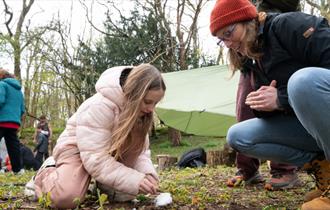 Mother watching daughter learning how to light a fire.