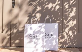 Cote bags with Cote at Home written on them outside front door
