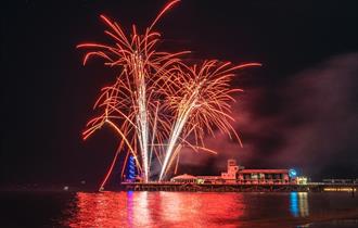 Image of a red firework going off over Bournemouth Pier