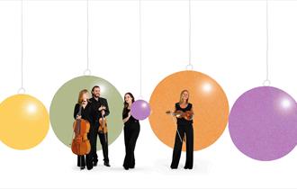 Image of 4 BSO musicians standing in front of giant Christmas baubles