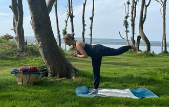 Yoga teacher in pose with Poole Harbour in the background.