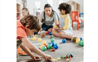 image shows children on the floor playing with toys