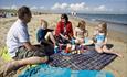 A family of five people having a picnic on Knoll Beach at Studland Bay in Dorset