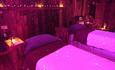 A dark pink room with two massage beds.