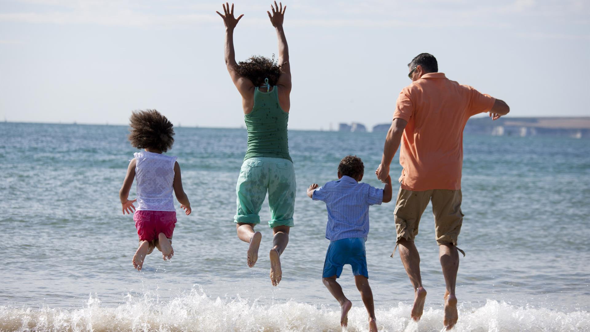Family jumping at sandbanks beach