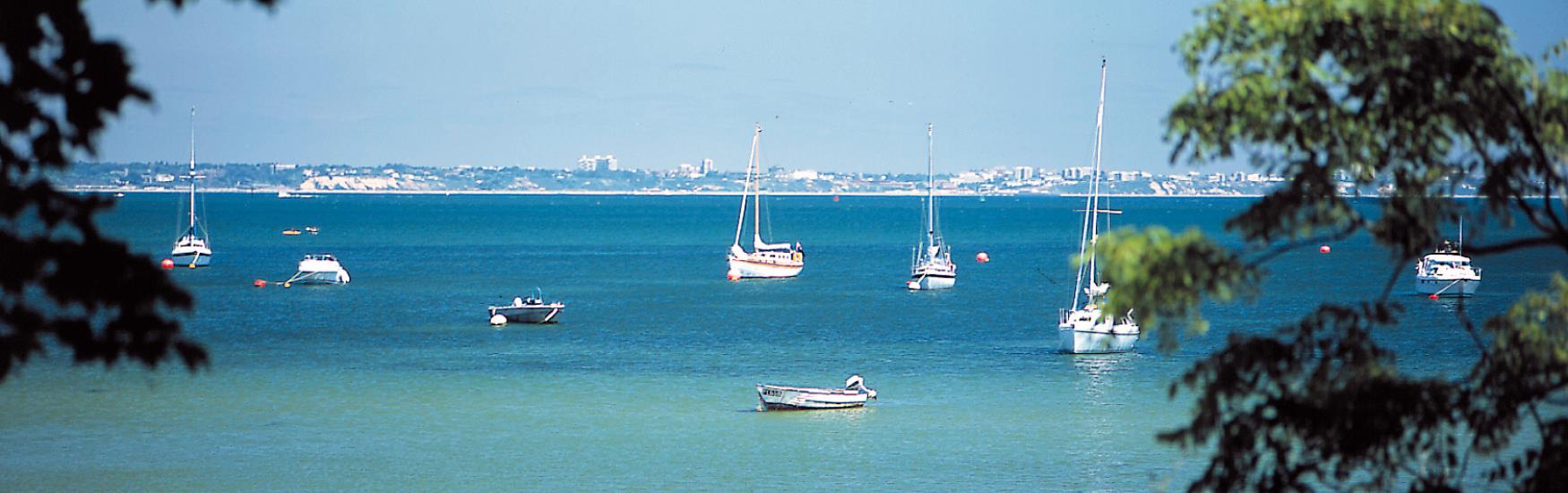 Boats moored near studland with Bournemouth and Pooles coast in the background