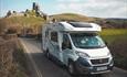 Campervan driving along road with corfe castle in the background