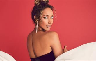 Leona Lewis  looking over her shoulder with a red background
