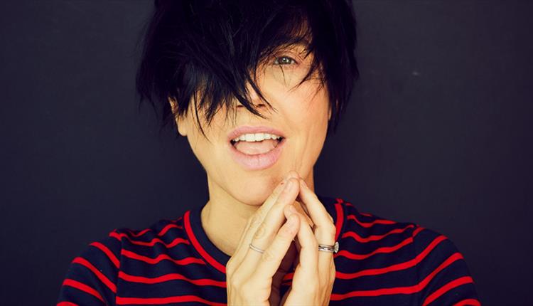 A woman with short cropped hair, wearing a black and red stripped top.