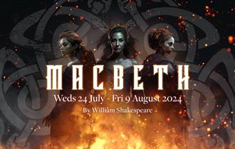 Three elegant witches dressed in black stand over a bonfire. Macbeth - Brownsea Open Air Theatre. 24 July to 9 August 2024