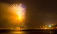A yellow hue of pyrotechnic wonder cascades across the skyline above Bournemouth Pier