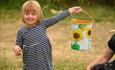 Child holding a bucket with sunflowers on