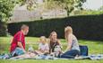 Young family enjoying a picnic with their kids on the lush green grass at Beaulieu