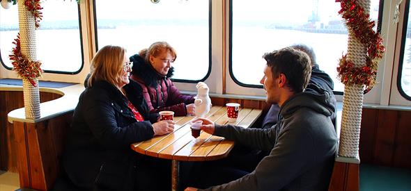 People sitting at a table on a boat drinking mulled wine