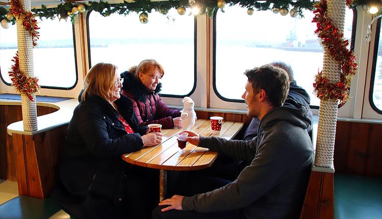People sitting at a table on a boat drinking mulled wine