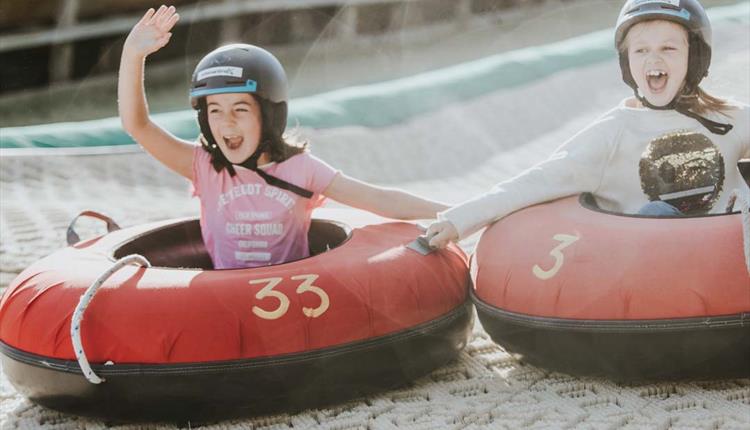 Two girls going down the dry ski slope together on their ringos