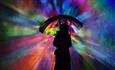 a woman's silhouette with umbrella in front of rainbow lighting