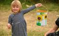 Little girl holding up a tin with painted sunflowers