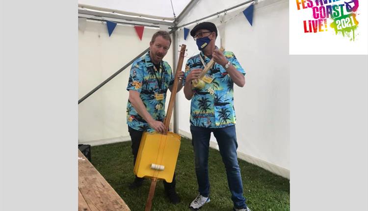 Two men in bright patterned shirts playing percussion in a tent